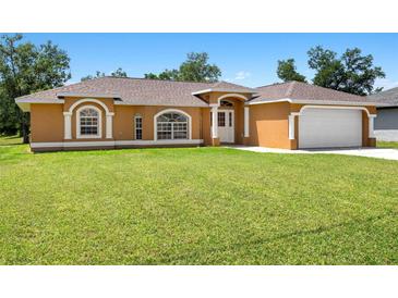 Charming one-story home featuring arched windows, a well-maintained lawn, and a two-car garage at 27255 Deep Creek Blvd, Punta Gorda, FL 33983
