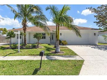 Charming single-story home featuring a well-manicured lawn, palm trees, and a white exterior at 3417 50Th W St, Bradenton, FL 34209