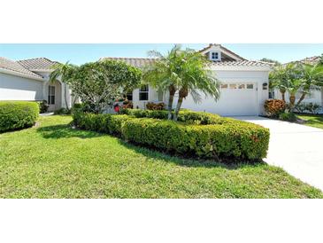 Beautifully landscaped front yard with lush green bushes, palm trees and a manicured lawn at 3870 Alamanda Dr, Sarasota, FL 34238