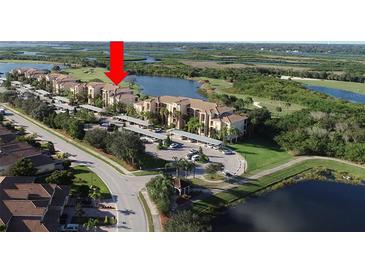 Beautiful aerial view of condo community with lakes, mature trees, and covered parking at 7803 Grand Estuary Trl # 205, Bradenton, FL 34212