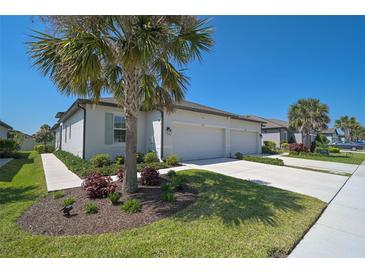 Beautiful home featuring a three-car garage, well-manicured lawn, and lush landscaping at 8553 Whispering St, Sarasota, FL 34240
