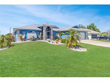Charming single-story home featuring a well-manicured lawn and decorative landscaping at 23088 Allen Ave, Port Charlotte, FL 33980