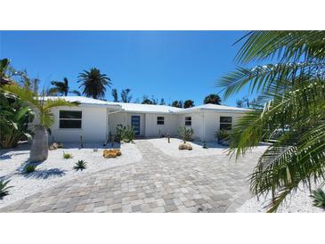 Charming single-story home featuring a lush, landscaped front yard and a brightly colored front door at 306 Island Cir, Sarasota, FL 34242