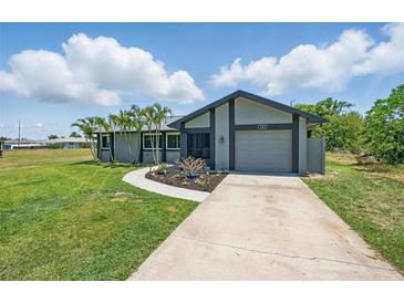 Charming single-story home with a well-maintained lawn, palm trees, and an inviting walkway leading to the front door at 3260 Pinetree St, Port Charlotte, FL 33952