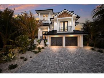 Beautiful two-story home with a two-car garage, balcony, and lush landscaping at 408 Magnolia Ave, Anna Maria, FL 34216