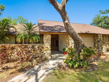 Charming home featuring a stone facade, mature landscaping, and a welcoming brick pathway leading to the front entrance at 4917 Hidden Oaks Trl, Sarasota, FL 34232