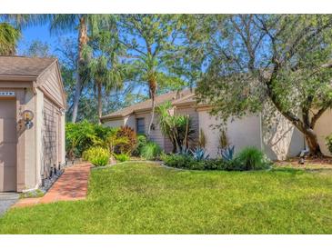 Landscaped front yard features lush green lawn, tropical plants, and a brick walkway to the front entrance at 4947 Greencroft Rd # 175, Sarasota, FL 34235