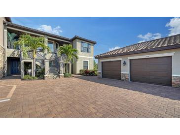 Elegant building featuring lush landscaping, private garages, and paver driveway at 5424 Cicerone St # 204, Sarasota, FL 34238