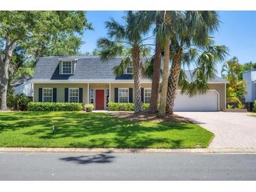 Charming home featuring a landscaped yard, palm trees, black shutters, and a bright red front door at 5504 Beneva Woods Circle, Sarasota, FL 34233