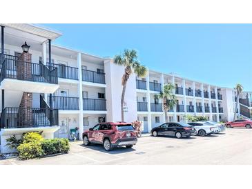 A clean three-story condo building with black wrought iron railings and covered parking on a bright, sunny day at 5901 Garden Ln # H23, Bradenton, FL 34207