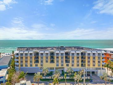 Luxury building with balconies overlooking ocean and beach with rows of palm trees in a sunny landscape at 915 Seaside Dr # 405 Weeks 22-23, Sarasota, FL 34242