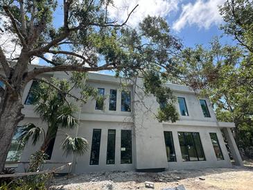 Modern home exterior featuring sleek windows, stucco, and mature trees at 1423 S Shade Ave, Sarasota, FL 34239