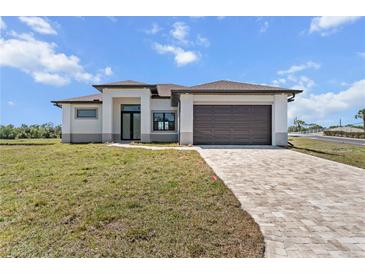 Modern, light gray home with a brown roof, matching brown garage door and a beautifully paved driveway at 197 Rotonda Cir, Rotonda West, FL 33947