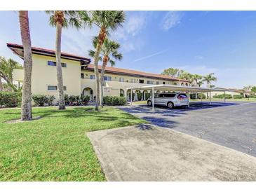 Condo exterior with well-maintained landscaping, covered parking, and mature palm trees on a sunny day at 3690 Pinecrest St # 124, Sarasota, FL 34232