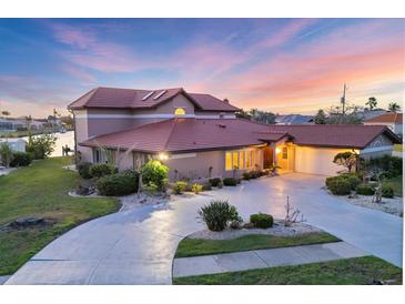 Stunning two-story home with a red tile roof, circular driveway, lush landscaping, and waterfront canal access at 4405 Harbor Blvd, Port Charlotte, FL 33952