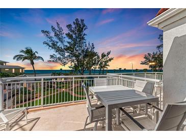 Relaxing balcony view featuring white patio furniture, tropical landscaping, and serene ocean backdrop at 5055 Gulf Of Mexico Dr # 232, Longboat Key, FL 34228