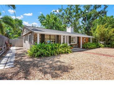 Charming stone home with lush landscaping, a covered porch, and a gravel yard at 528 45Th St, Sarasota, FL 34234
