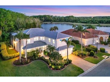 Stunning lakefront home with lush landscaping, a tile roof, and a brick driveway at 7538 Camden Harbour Dr, Bradenton, FL 34212