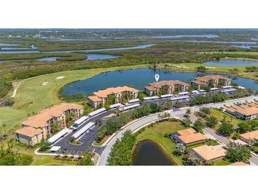 Stunning aerial view of lakeside condos with golf course, mature trees, and convenient covered parking at 7803 Grand Estuary Trl # 102, Bradenton, FL 34212