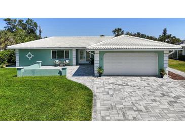 Charming teal home featuring a spacious two-car garage, tile roof, and beautifully paved driveway at 217 Giotto Dr, Nokomis, FL 34275