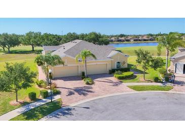 Stunning single-story home featuring lush landscaping, a brick driveway, and a three-car garage at 302 Crystal Downs Ct, Sun City Center, FL 33573