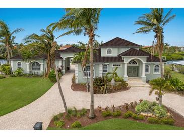 Elegant two-story waterfront home with lush landscaping and a circular brick driveway lined with palm trees at 4355 Pompano Ln, Palmetto, FL 34221
