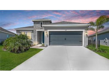 Charming single-story home with a two-car garage, landscaped lawn, and stone facade accents at 11869 Richmond Trl, Parrish, FL 34219
