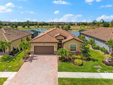 Stunning lake view home with a brick paved driveway, two car garage and beautifully landscaped yard at 12501 Cinqueterre Dr, Venice, FL 34293