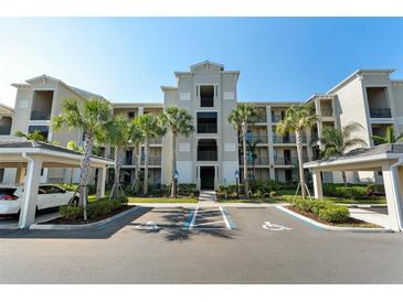Condominium complex with light gray exterior, palm trees, covered parking, and handicap parking spaces at 17902 Gawthrop Dr # 107, Bradenton, FL 34211