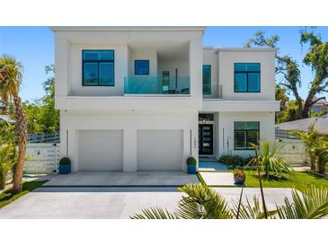 Modern two-story home with a two-car garage, balcony with glass railings, and manicured landscaping at 1842 Kenilworth St, Sarasota, FL 34231