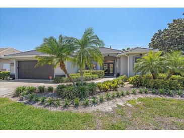 Charming home with lush landscaping, palm trees, and a tile roof on a sunny day at 5554 Eastwind Dr, Sarasota, FL 34233
