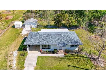 Charming single-story home showcasing a well-maintained lawn, shingled roof, and detached garage at 80 Liles St, Terra Ceia, FL 34250