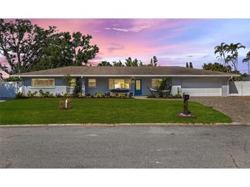 Charming single-story home featuring a well-manicured lawn, blue door, and attached two-car garage at 2202 Alpine Ave, Sarasota, FL 34239