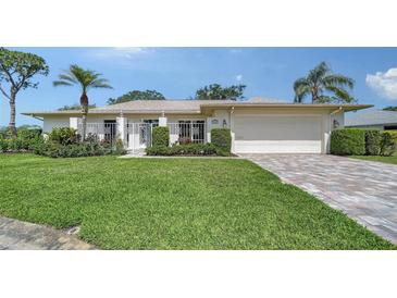 Well-maintained single-story home featuring a lush green lawn, a two-car garage, and tropical landscaping at 3572 Ferndell, Sarasota, FL 34235