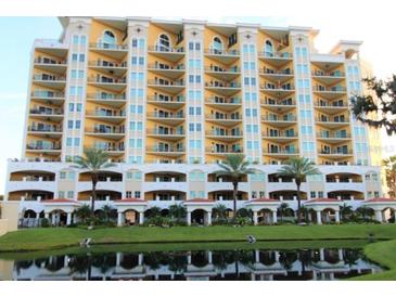 Beautiful multi-story condo building with balconies, palm trees, and pond reflections at 501 Haben Blvd # 704, Palmetto, FL 34221