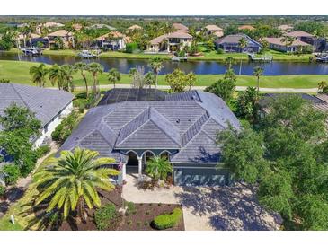 An aerial view showcases the tile roof, and the surrounding water features and lush landscaping in this waterfront community at 10411 Winding Stream Way, Bradenton, FL 34212