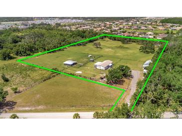 Expansive aerial view showcasing the home, surrounding acreage, and outbuildings within a green-lined property boundary at 5235 Spencer Parrish Rd, Parrish, FL 34219
