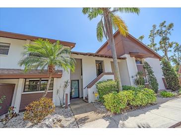 Inviting condo with lush landscaping, mature palm trees, and brown and white exterior paint scheme at 6040 Oak Creek Ln # 1822, Bradenton, FL 34210