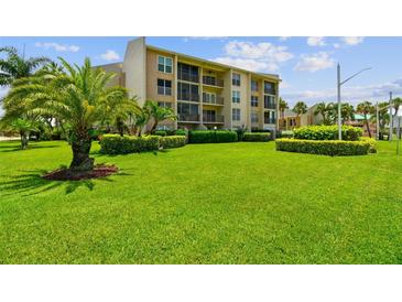 Beautiful condo exterior with well-manicured green lawn and tropical landscaping at 845 Benjamin Franklin Dr # 101, Sarasota, FL 34236