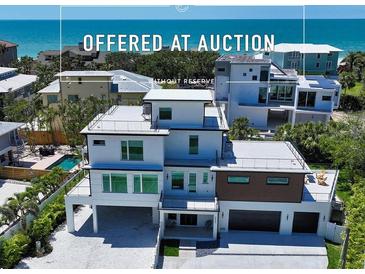 Stunning three-story beach house featuring modern design, a flat roof, and a spacious two-car garage at 8800 Midnight Pass Rd, Sarasota, FL 34242