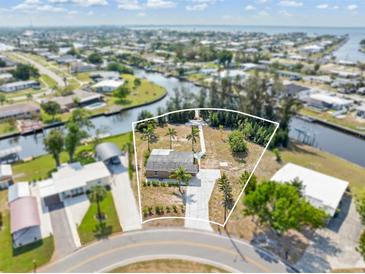 An aerial view of a single Gathering home on a canal with a large driveway, mature trees and landscaping at 891 Palmetto Ne Dr, Port Charlotte, FL 33952