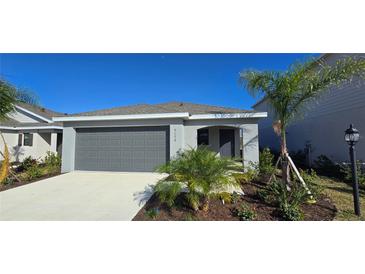 Charming single-story home with a gray two-car garage, well-maintained lawn, and lush tropical landscaping at 9176 Tequila Sunrise Dr, Sarasota, FL 34241