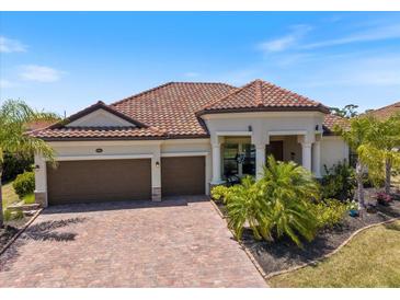 Charming single-story home featuring a tile roof, mature landscaping, and a two-car garage on a sunny day at 20655 Valprato Ct, Venice, FL 34293