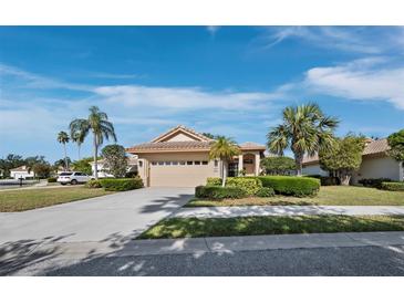 Charming single-story home with a well-manicured lawn, mature trees, and a two-car garage on a sunny day at 3835 Alamanda Dr, Sarasota, FL 34238