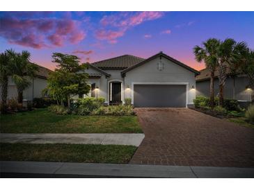 Charming home featuring a lush, landscaped front yard, brick paver driveway, and two-car garage at 6266 Mesa Gln, Bradenton, FL 34203
