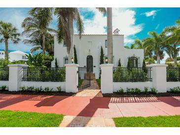 Charming two-story home with a black metal fence and a beautiful array of mature palm trees at 76 S Washington Dr, Sarasota, FL 34236