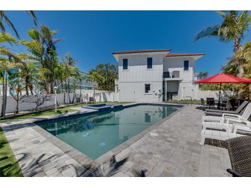 An inviting backyard pool and patio area is adjacent to a pristine white home with a red tile roof at 803 Gladiolus St, Anna Maria, FL 34216