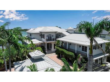 Stunning two-story home with a light-colored exterior, metal roof, balconies, and lush tropical landscaping at 1435 Westway Dr, Sarasota, FL 34236