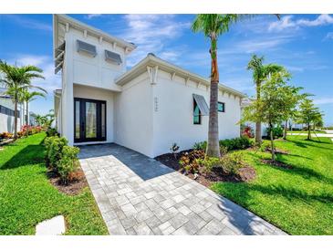Modern home exterior featuring a paved walkway, manicured lawn, and lush tropical landscaping at 5939 Redbay Blvd, Bradenton, FL 34210