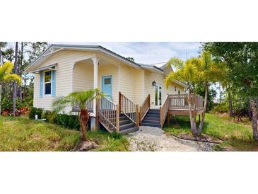 Charming home with pale yellow siding, a baby blue front door, and a raised deck with steps leading down to the yard at 8297 Strasse Blvd, Punta Gorda, FL 33982